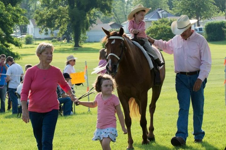 A family leading a young rider on horseback