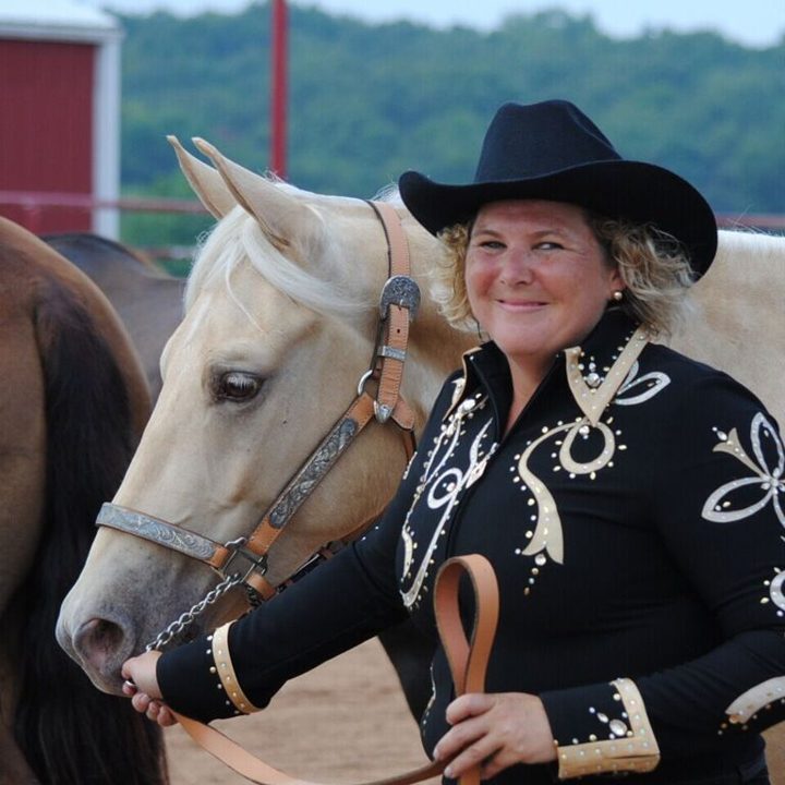 Exhibitor leading a palomino horse in the halter class